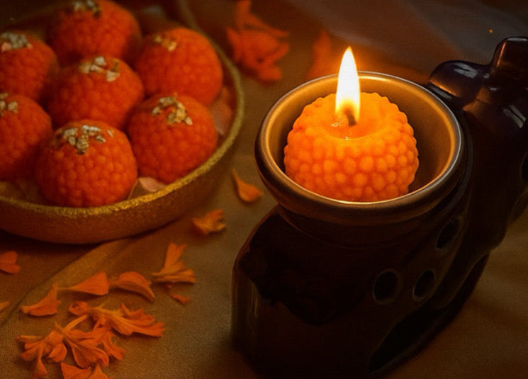Advertisement for handcrafted laddoo candles with a lit candle and laddus on a dark background.